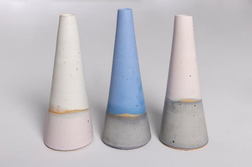 Tre farvede kegle-formede keramiske genstande med en kombination af pastel- og neutrale nuancer, placeret på en neutral baggrund. (2)