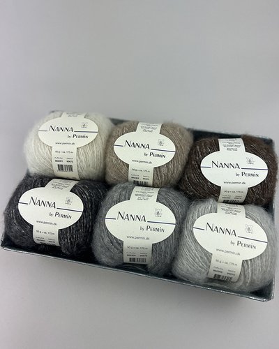 Billede af seks nøgler garn i forskellige grå, brun og hvide nuancer, mærket "Nanna by Permin", arrangeret i en metalbakke.