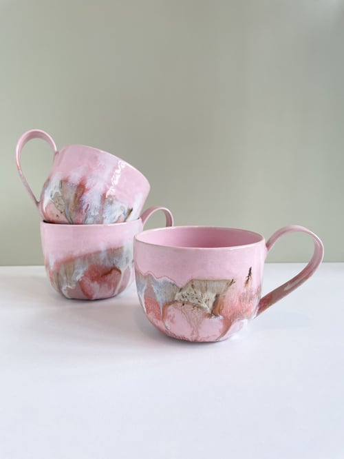 Tre rosa keramikkopper med kunstneriske, abstrakte mønstre i brun og grå, placeret mod en neutral baggrund. (1)