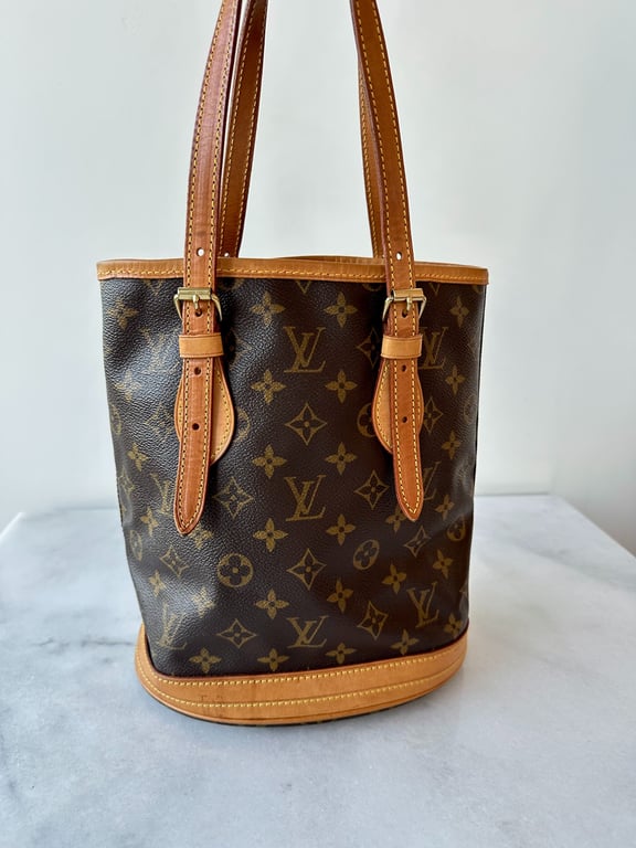 Brun Louis Vuitton taske i lærred med klassisk monogrammønster og lysebrune læderremme placeret på en marmorflade.