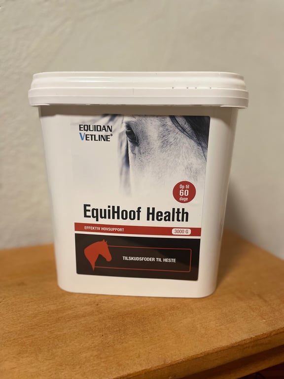 Beholder med EquiHoof Health tilskudsfoder til heste, mærket Equidan Vetline, med billede af en hest og tekst om effektiv hovsupport.