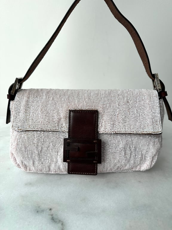 Håndtaske med perlebroderi i lyserødt og hvidt med mørkebrunt læderbæltespænde og justerbar skulderrem.