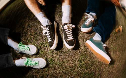Fire personer sidder på græsset med forskellige sneakers og hvide sokker på. (1)