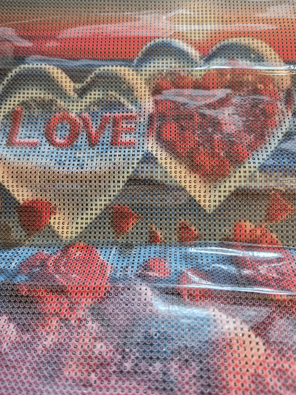 Billede af et kærlighedsbudskab med teksten "LOVE YOU" og hjerteformede figurer, set gennem et perforeret lag med bogstaver.