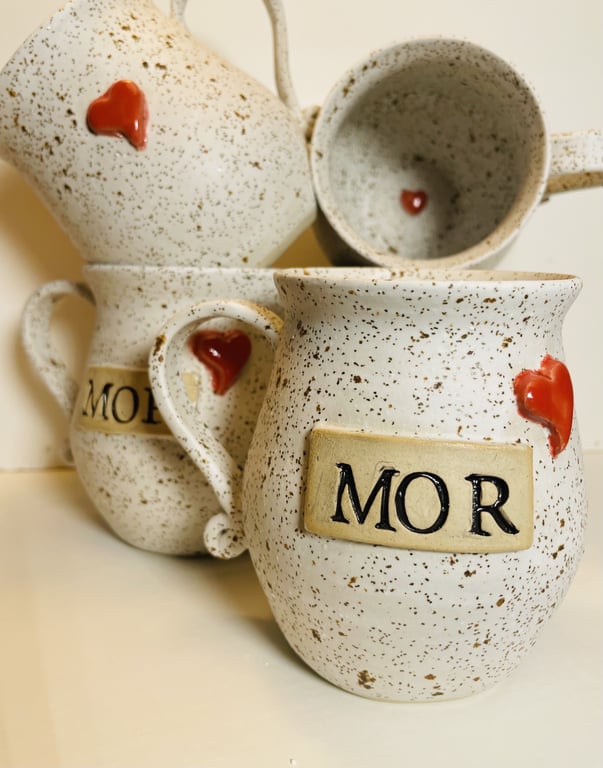 Krukker og kopper i beige med sorte prikker, dekoreret med røde hjerter og med teksten "MOR" på.