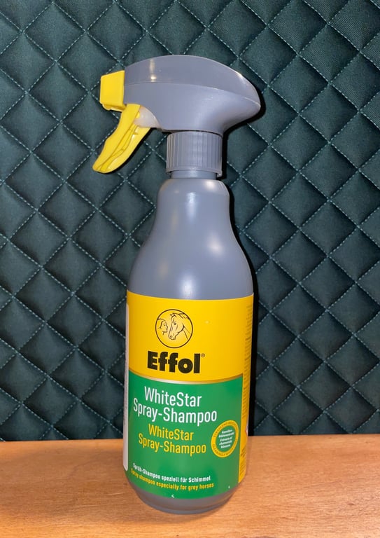 Effol WhiteStar spray-shampoo flaske med grå og gul label, placeret på træbord mod en quiltet, mørk baggrund.