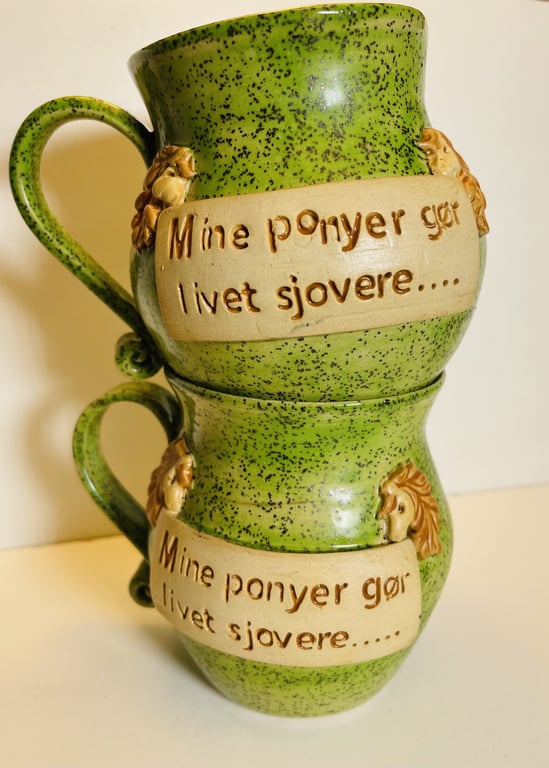 To grønne keramikkrus med påskriften "Mine ponyer gør livet sjovere" og udsmykket med små ponyfigurer.
