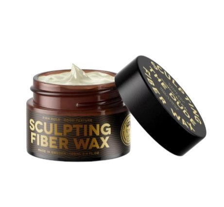 Åben krukke med sculpting fiber voks til hårstyling med sort låg ved siden af, på hvid baggrund.