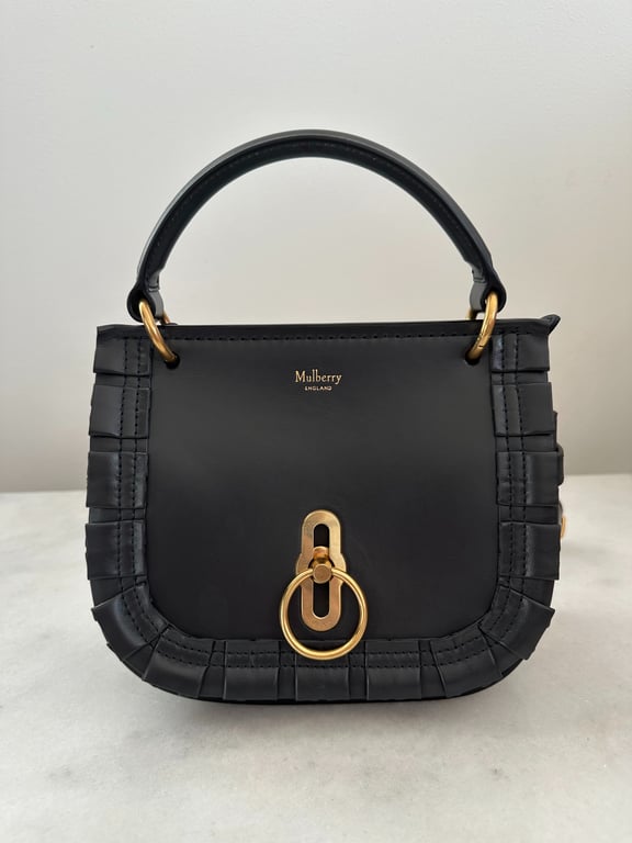 Sort Mulberry håndtaske i læder med guld hardware og dekorative folder langs kanterne.