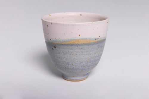 Keramik kop med blå og lyserød glasur, placeret på hvid baggrund.