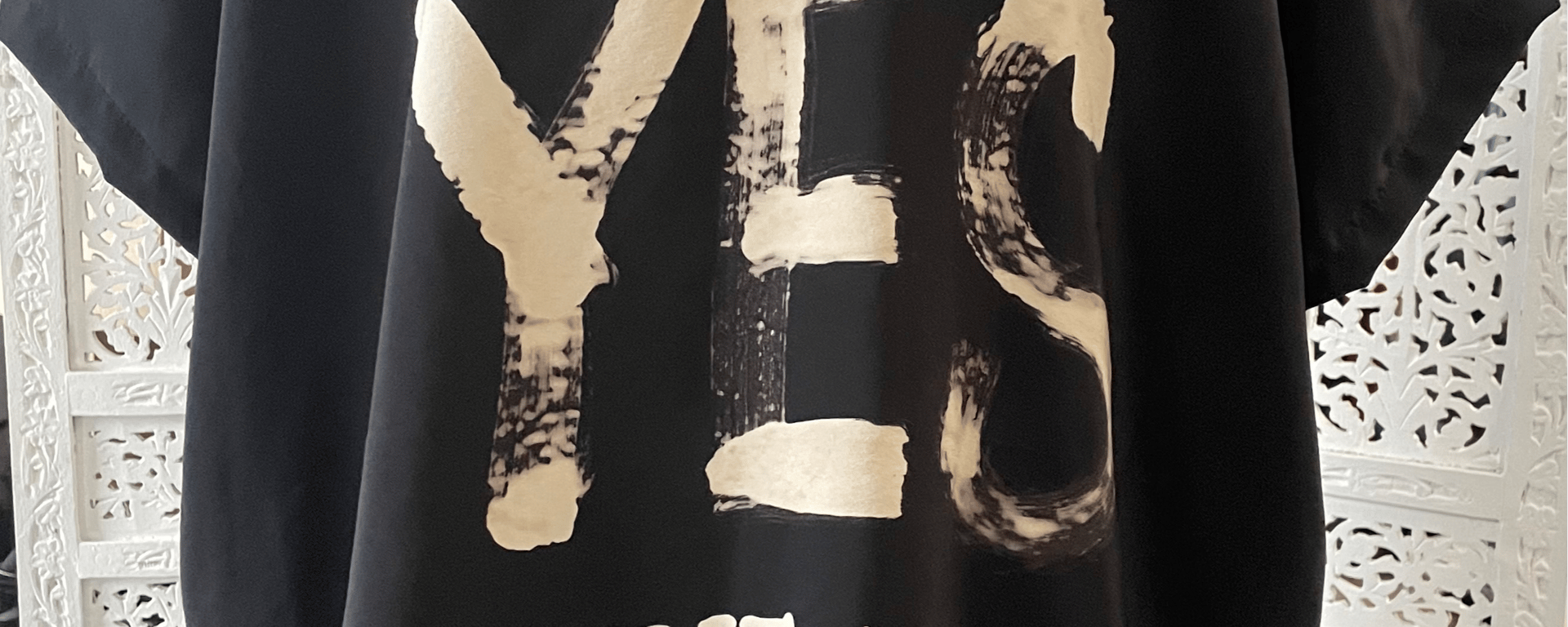 Sort T-shirt med stort, hvidt print af ordet "YES" på forsiden.