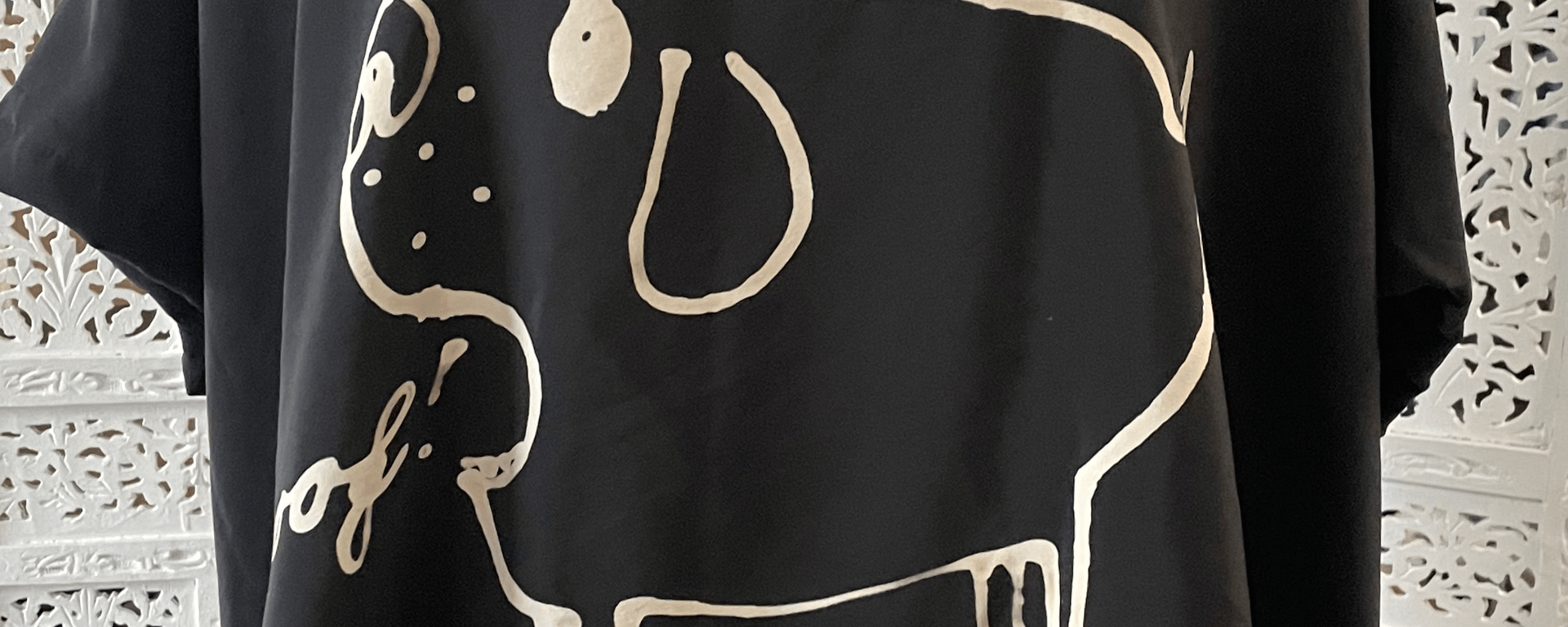Sort t-shirt med hvidt, tegnet motiv af en hund og teksten "woof!".