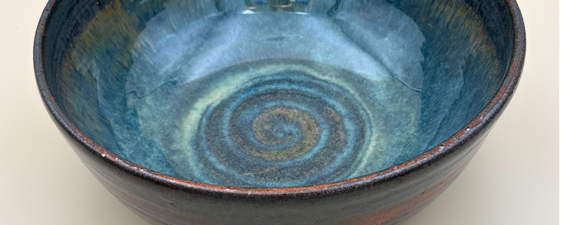 Blå keramisk skål med spiral mønster i bunden og glaseret finish.