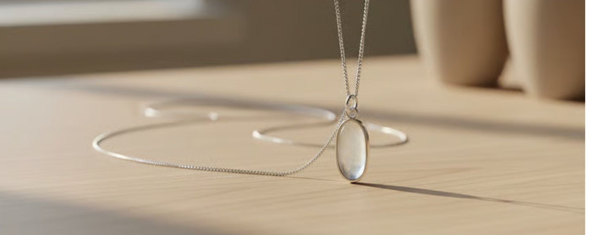 Nærbillede af en læderpose med et intentionskort, en hvid perlearmbånd, en sort sten og en guldring med en hvid perle.