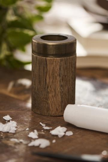 Billede af en træstøtte til et hvidt stearinlys, placeret på et træbord med smeltet voks omkring.