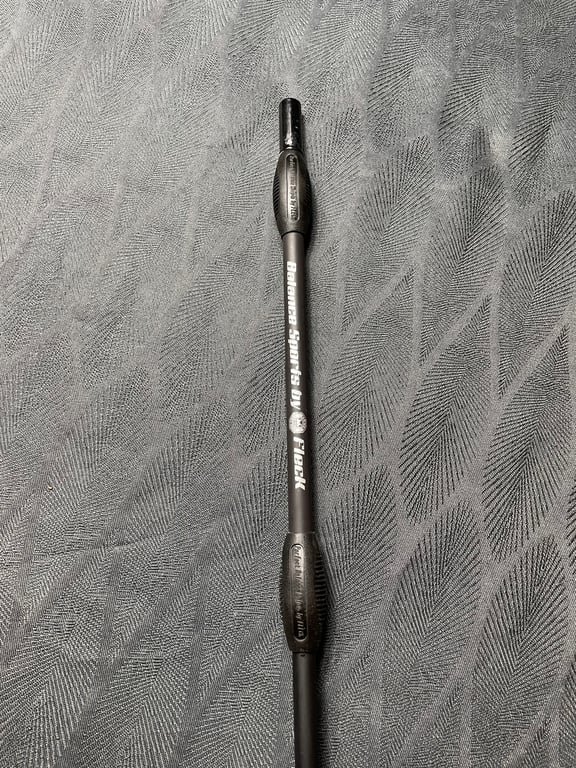 Billede af en sort pil-shaft med teksten "Rubber-Sports by Black" på en grå tekstureret overflade.