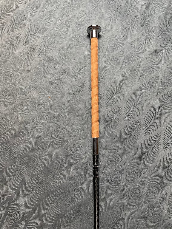 Baseballbat med brunt læderhåndtag lagt på gråt mønstret stof.
