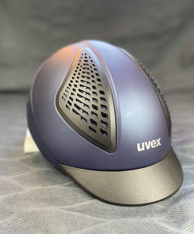 Blå og grå ridehjelm med ventilationshuller og mærket "uvex" foran.