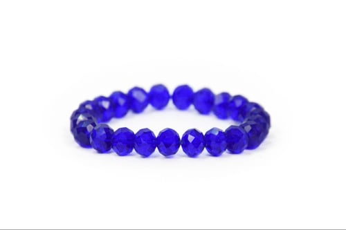 Armbånd lavet af facetterede, mørkeblå perler på hvid baggrund. (2)