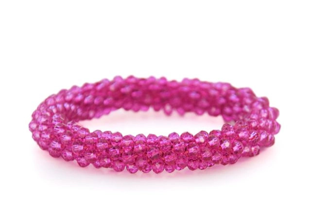 Rosa glasperler samlet som et elastisk armbånd på hvid baggrund.