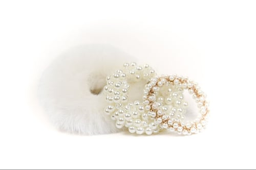 Hvide og perlebesatte hårpynt, inklusive en fluffet scrunchie og to elastikker med perler, på hvid baggrund. (2)
