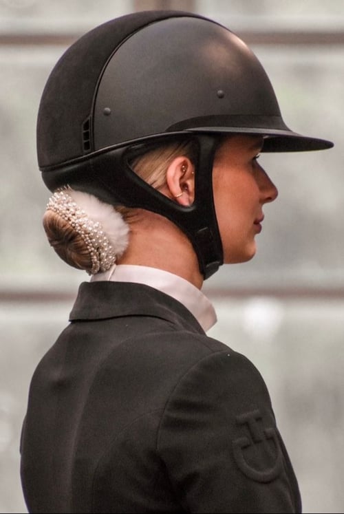 Kvinde i ridehjelm og ridesjaket med elegant opsat hår dekoreret med perler, set fra siden. (1)