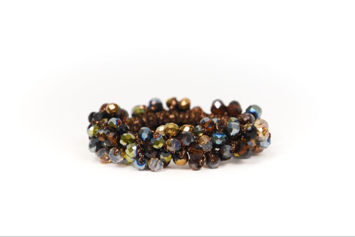 Håndlavet elastik armbånd med små flerfarvede facetterede perler i nuancer af brun, grøn og blå.