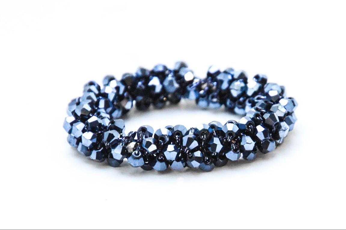 Blåt armbånd lavet af facetterede perler på hvid baggrund.