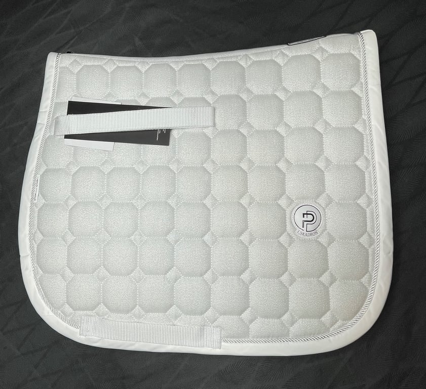 Hvidt Eskadron sadelunderlag med quiltet mønster og logo på sort baggrund.