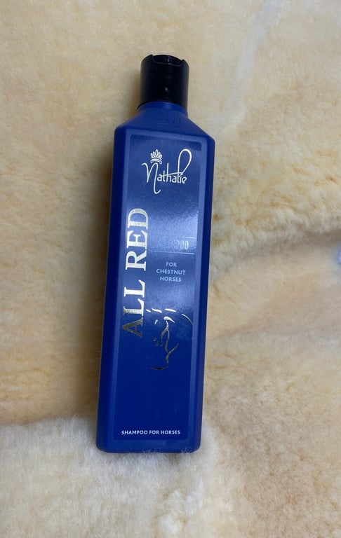 Flaske med blå shampoo til heste, mærket "Nathalie ALL RED for chestnut horses".
