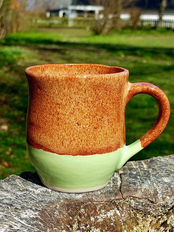 Kop med hank i brun og limegrøn glasur.    