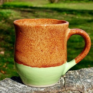 Kop med hank i brun og limegrøn glasur.     – produktbillede