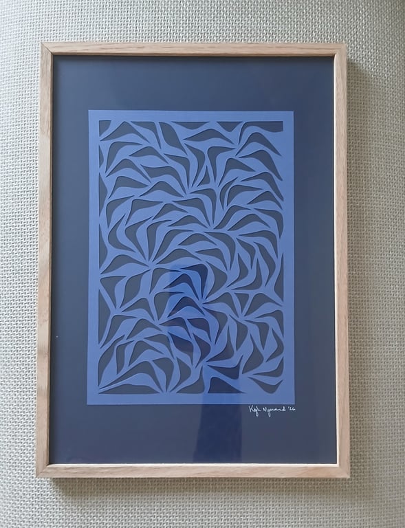 Billedet viser en kunstplakat med abstrakt, blåt mønster i træramme, hængende på en væg med beige tekstur.