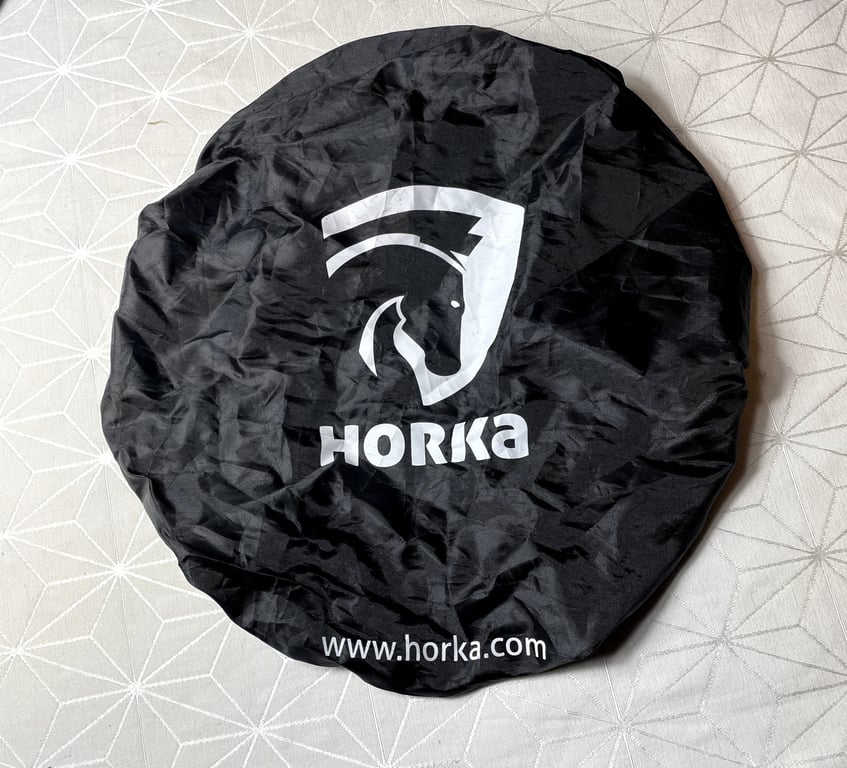 Sort rundt overtræk med hvidt logo af hestehoved og teksten "HORKA" samt webadresse "www.horka.com".