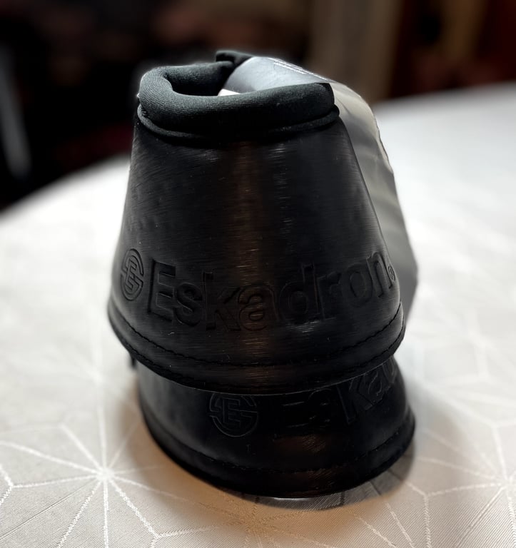 Sort hestebeskytter med logoet "Eskadron" påsat, vist bagfra på en hvid overflade.