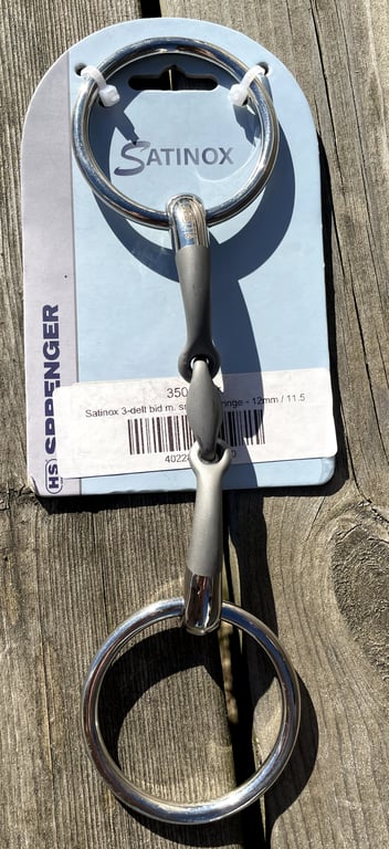 Bidd til hest i rustfrit stål, mærket "Satinox" monteret på en blå papplade med teksten "HS Opherdinger".