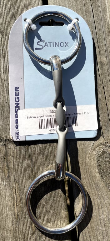 Tre-delt bidle med store ringe fra mærket Satinox, monteret på emballage med brunt træ i baggrunden.