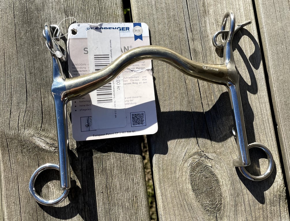 Biddet med messing-mundstykke og stålkindstykker, lagt på træbord med prisskilt fra HS Serpenger.
