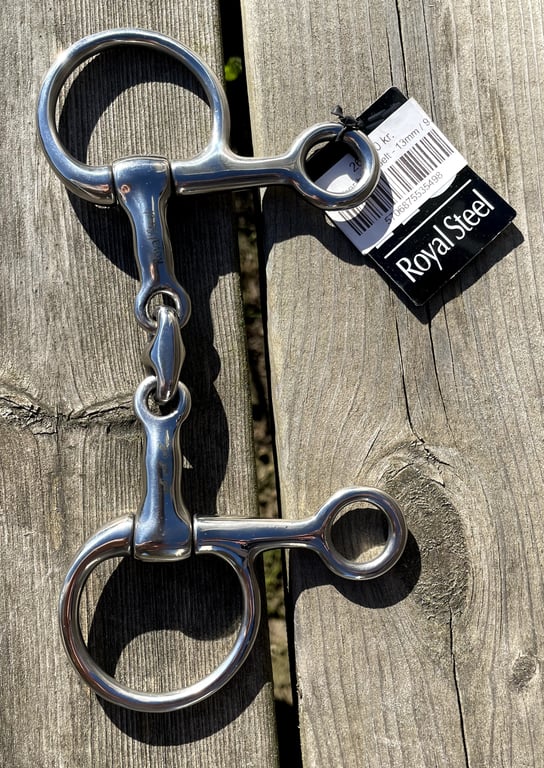 Løssprunget bid af rustfrit stål med etikette fra Royal Steel liggende på træbord.