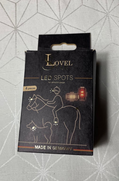 Sort æske med tekst "Lovel LED Spots", indeholdende 4 LED-lys til hest, rytter og hund, lavet i Tyskland.