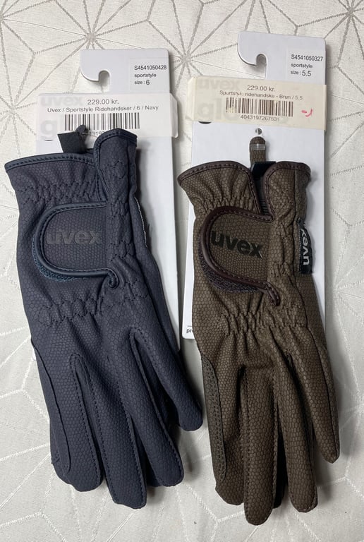 To par ridehandsker fra mærket Uvex, den ene i navyblå størrelse 6 og den anden i brun størrelse 5,5, begge med prisetiket på 229,00 kr.