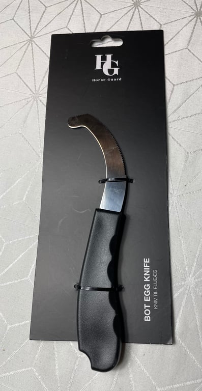 Sort botæggekniv med sort håndtag på sort emballage med teksten "Horse Guard" og "BOT EGG KNIFE KNIV TIL PLEJEG".