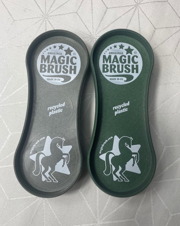 To Magic Brush rengøringsbørster i genbrugsplast, den ene i grå og den anden i grøn, placeret på et mønstret hvidt underlag.
