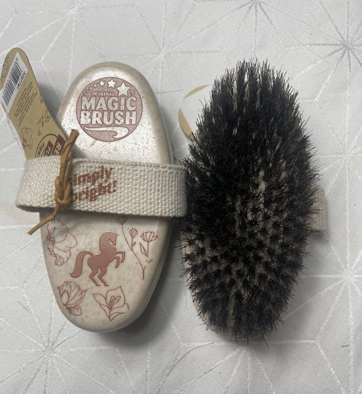 Børste med naturlige børstehår og en hvid base med tryk af hest og blomster samt en elastisk strop med teksten "Simply Bright".