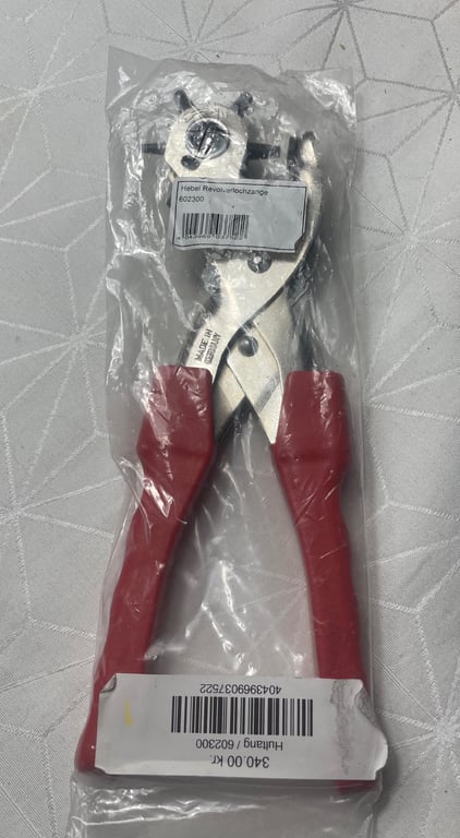 Billede af røde håndtag tang i en gennemsigtig plastikpose med etiketter på.