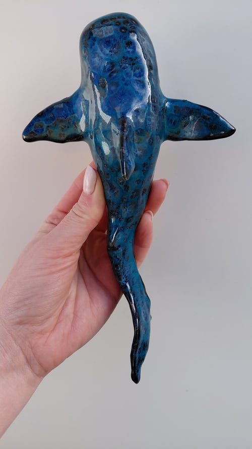 Hånd der holder en blå keramisk figur formet som en havskildpadde set ovenfra. (1)