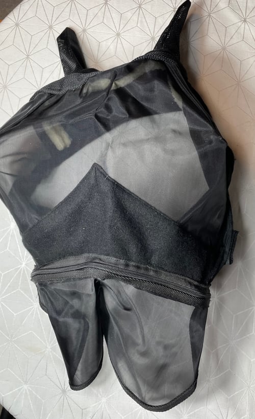 Sort hestemaske med net og blødt materiale, lagt på et mønstret underlag. (1)