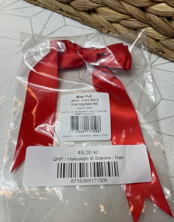 Rødt hestebånd i klar plastikpose med pris- og stregkodelabels på hvid baggrund.