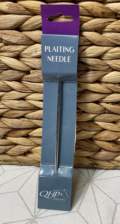 Billede af en flette-nål i sin originale emballage med teksten "PLAITING NEEDLE" på forsiden, foran en flettet kurv.