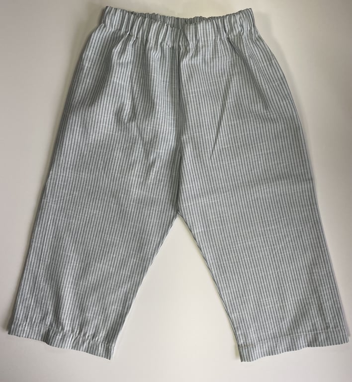 Et par lyseblå og hvide sweatpants med tynde lodrette striber og elastisk talje, lagt fladt på en lys baggrund.